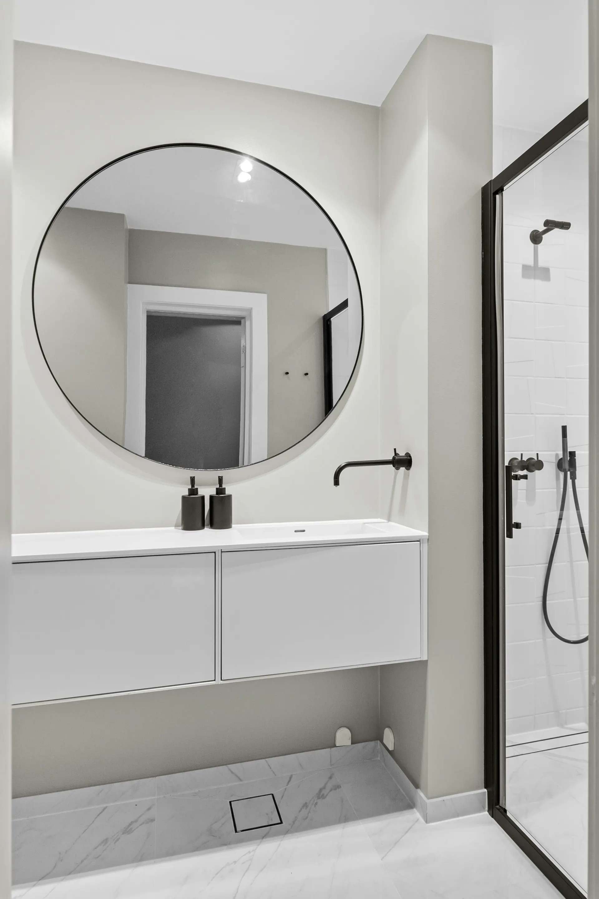 White bathroom with large round mirror — light, primary suite bath direction