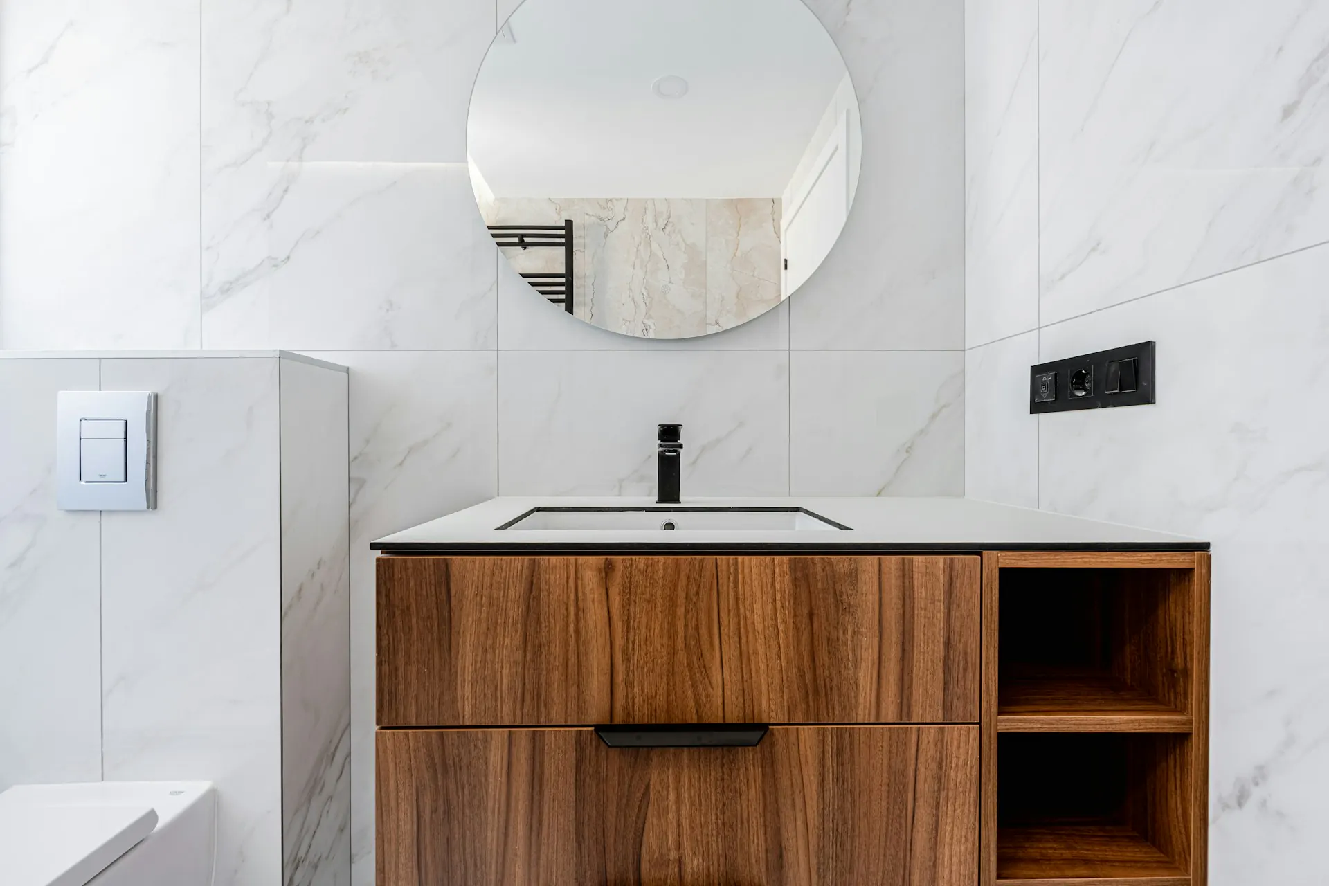 Bathroom vanity in a tiled surround with round mirror — representative of the choice between styles, finishes, and configurations